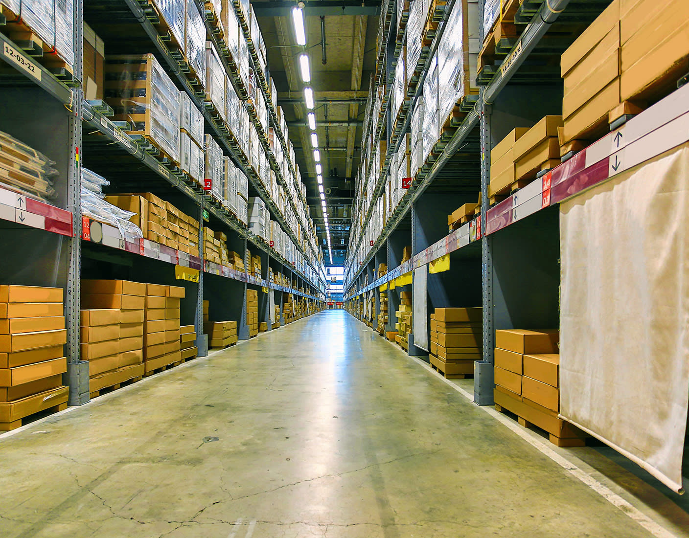 A long aisle in a warehouse, showcasing shelves filled with various products and equipment.
